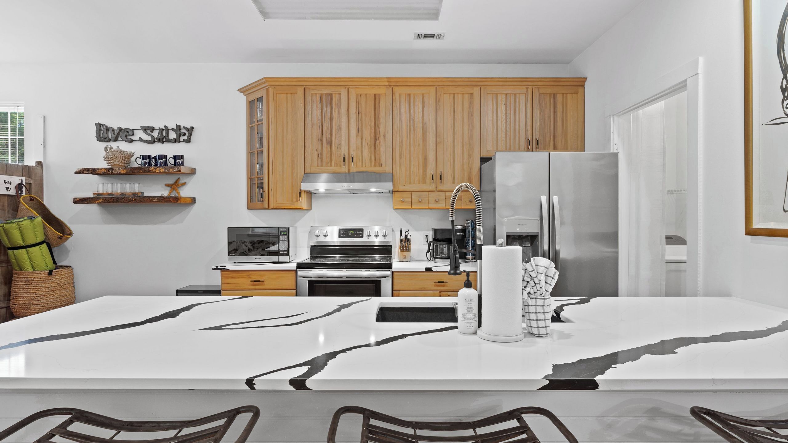 A modern kitchen with wooden cabinets, stainless steel appliances, and a marble island.
