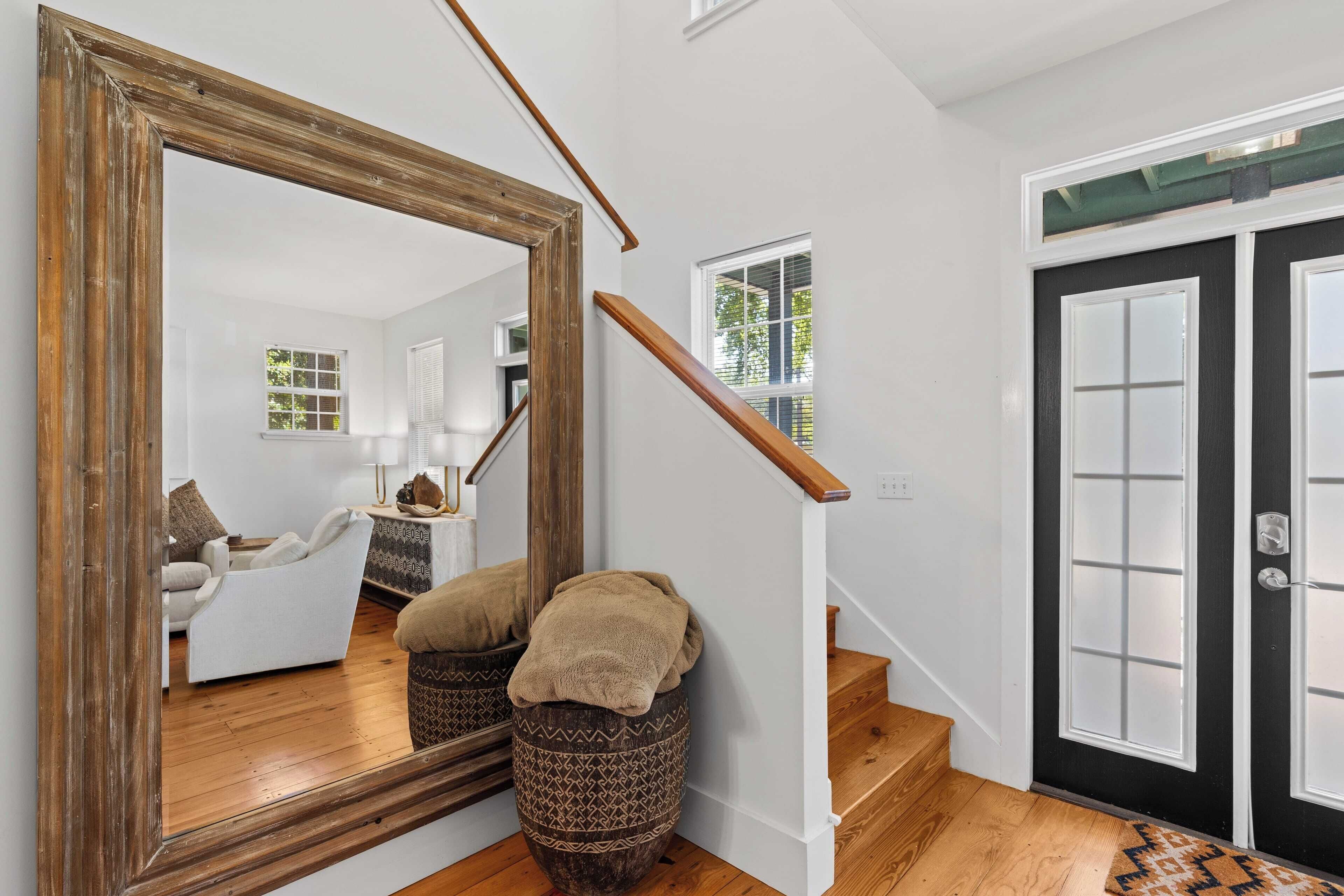 A staircase with a wooden handrail leading to a black door with glass panels.