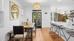 A modern kitchen with a wooden island, bar stools, and a hanging light fixture. - Coastal Soul 393 by Avantstay Near Boat Ramp & Bay, Private Yard (Santa Rosa Beach)