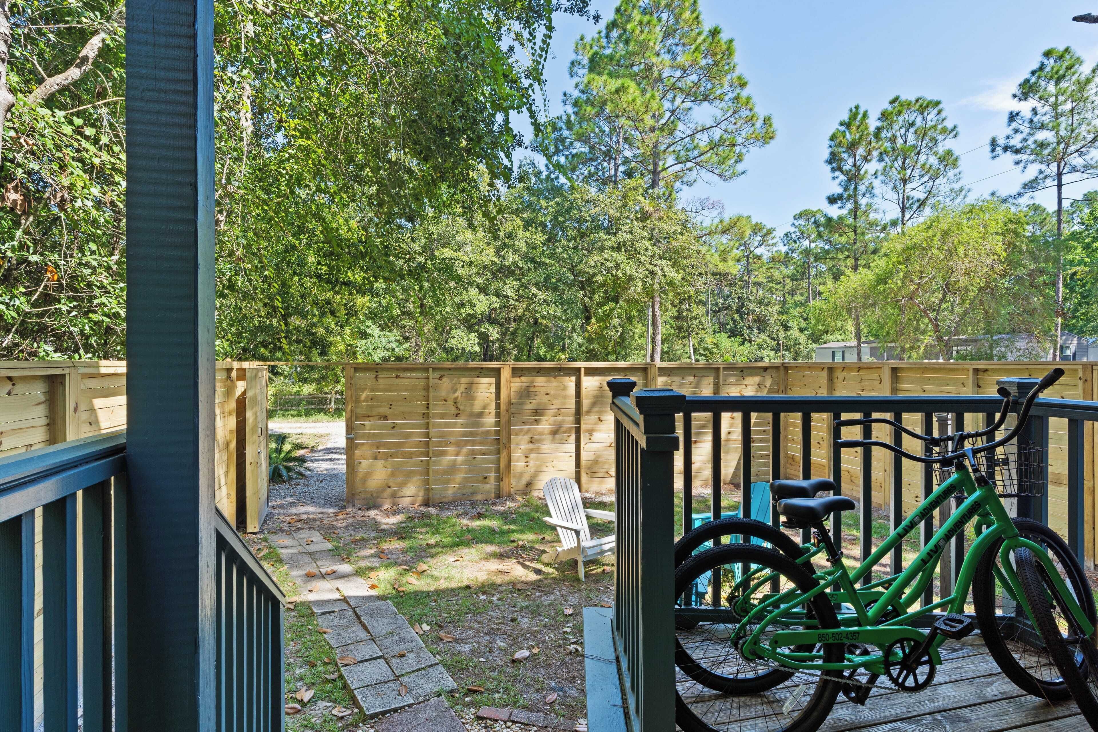 A wooden deck with a green bicycle and a white chair.