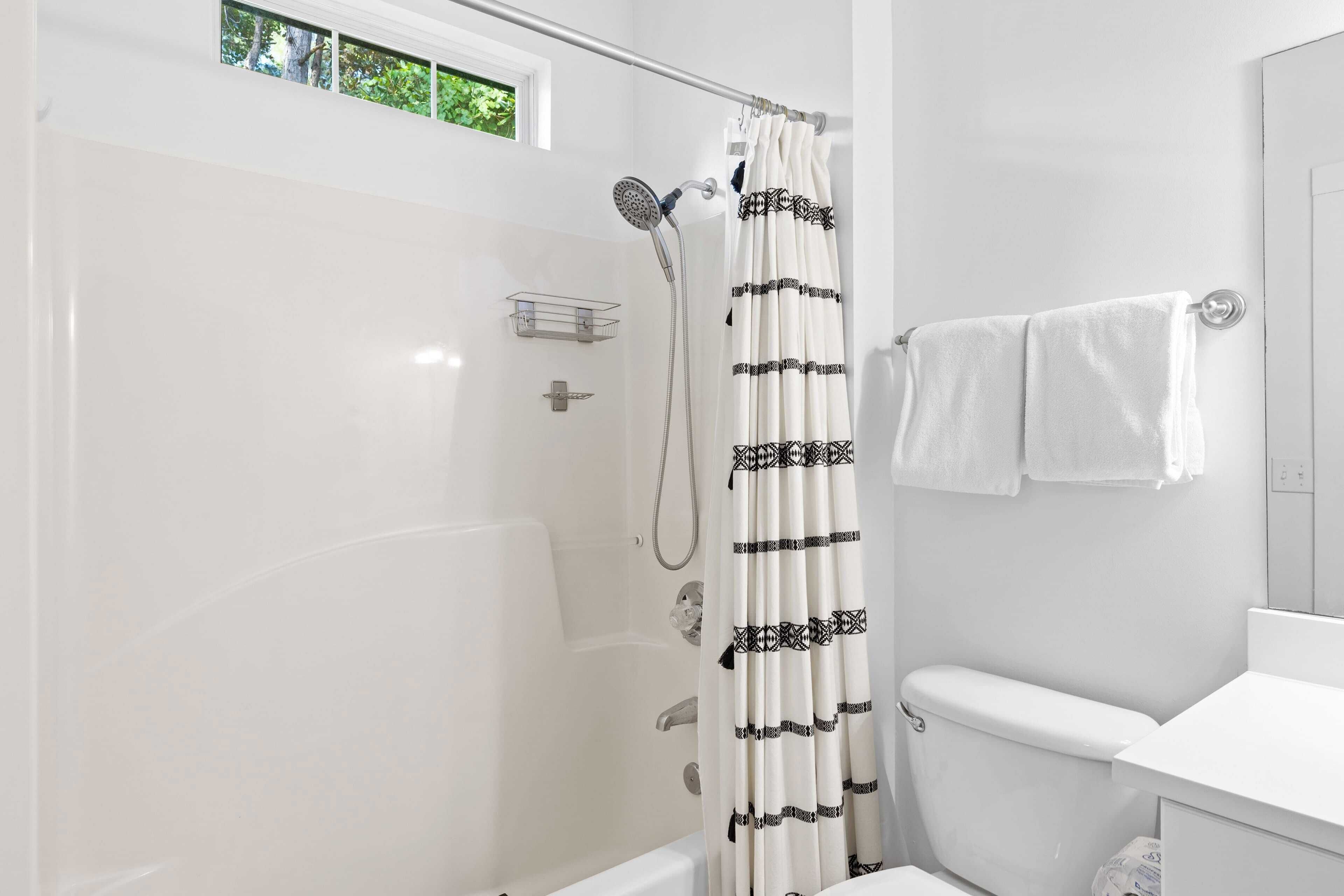 Ein modernes Badezimmer mit einer Duschkabine aus Glas, einer weißen Toilette und einem Handtuchhalter mit zwei weißen Handtüchern.