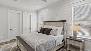 A bedroom with a bed, nightstands, a lamp, and a window with blinds. - 30A Salt Life by Avantstay Golf Cart + Pool Blue Mountain (Santa Rosa Beach)