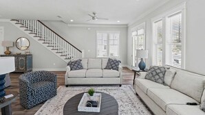 A spacious living room with a staircase, two sofas, a coffee table, and a side table with a lamp. - 30A Salt Life by Avantstay Golf Cart + Pool Blue Mountain (Santa Rosa Beach)