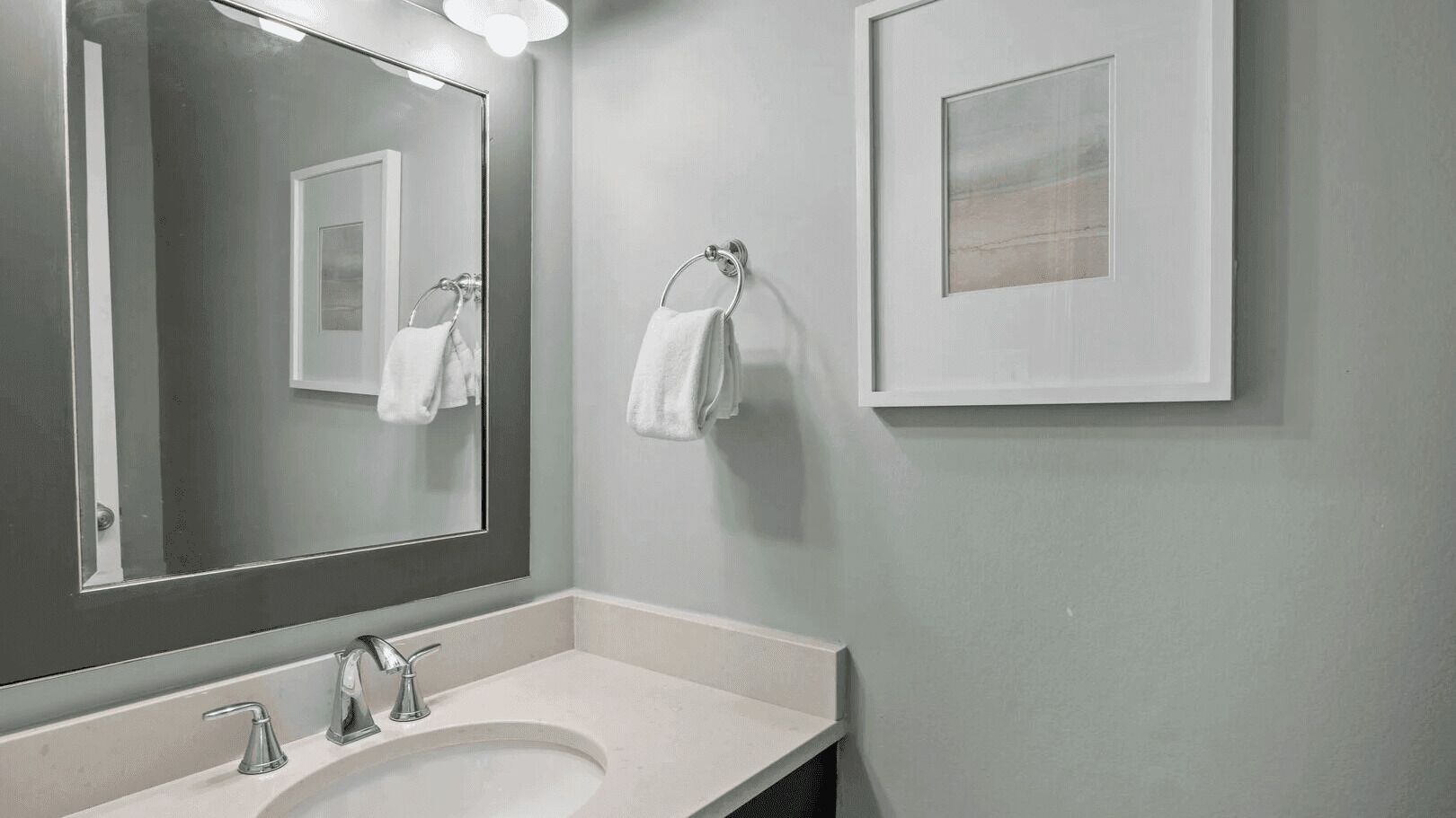 Baño con lavamanos, espejo y toallero.