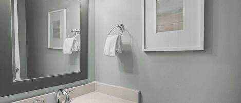 Baño con lavamanos, espejo y toallero.