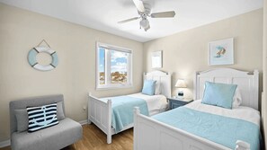 A bedroom with two beds, a window with a view, a ceiling fan, and a wall-mounted light fixture.