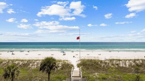 A beach with a flag, sand, and ocean.