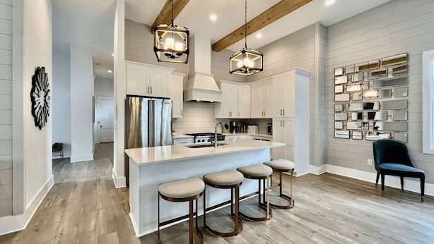 A modern kitchen with a central island, bar stools, pendant lighting, and a built-in wine rack.