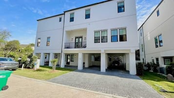Un immeuble d’appartements moderne à deux étages, doté d’une entrée abritée et d’un petit balcon.