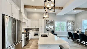 A modern kitchen with white cabinetry, stainless steel appliances, and a central island with a sink.