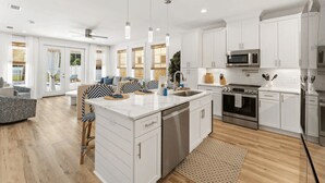 Une cuisine moderne avec des meubles blancs, des appareils en acier inoxydable et un îlot central.