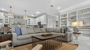 A modern living room with a sectional sofa, a wooden coffee table, and a dining area with a bench.