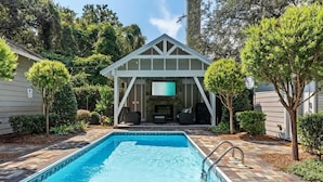 A rectangular swimming pool with a built-in deck, surrounded by a brick walkway.