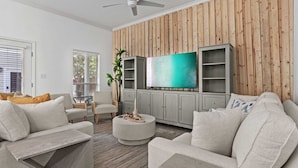 A modern living room with a wooden panel wall, a flat-screen TV, and a grey cabinet.
