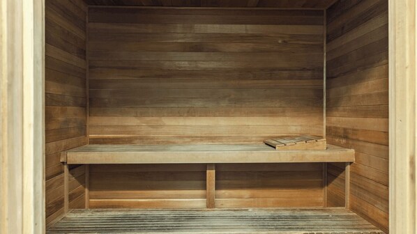 A wooden sauna with a bench and a small table.