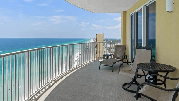 A balcony with a view of the ocean, a chair, a small table, and a window. - Bahama Breeze by Avantstay Gulf Front, 2 Pools, Beach Chairs Included! (Panama City Beach)