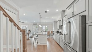 Una cocina amplia con una isla central, electrodomésticos de acero inoxidable y una escalera de madera.