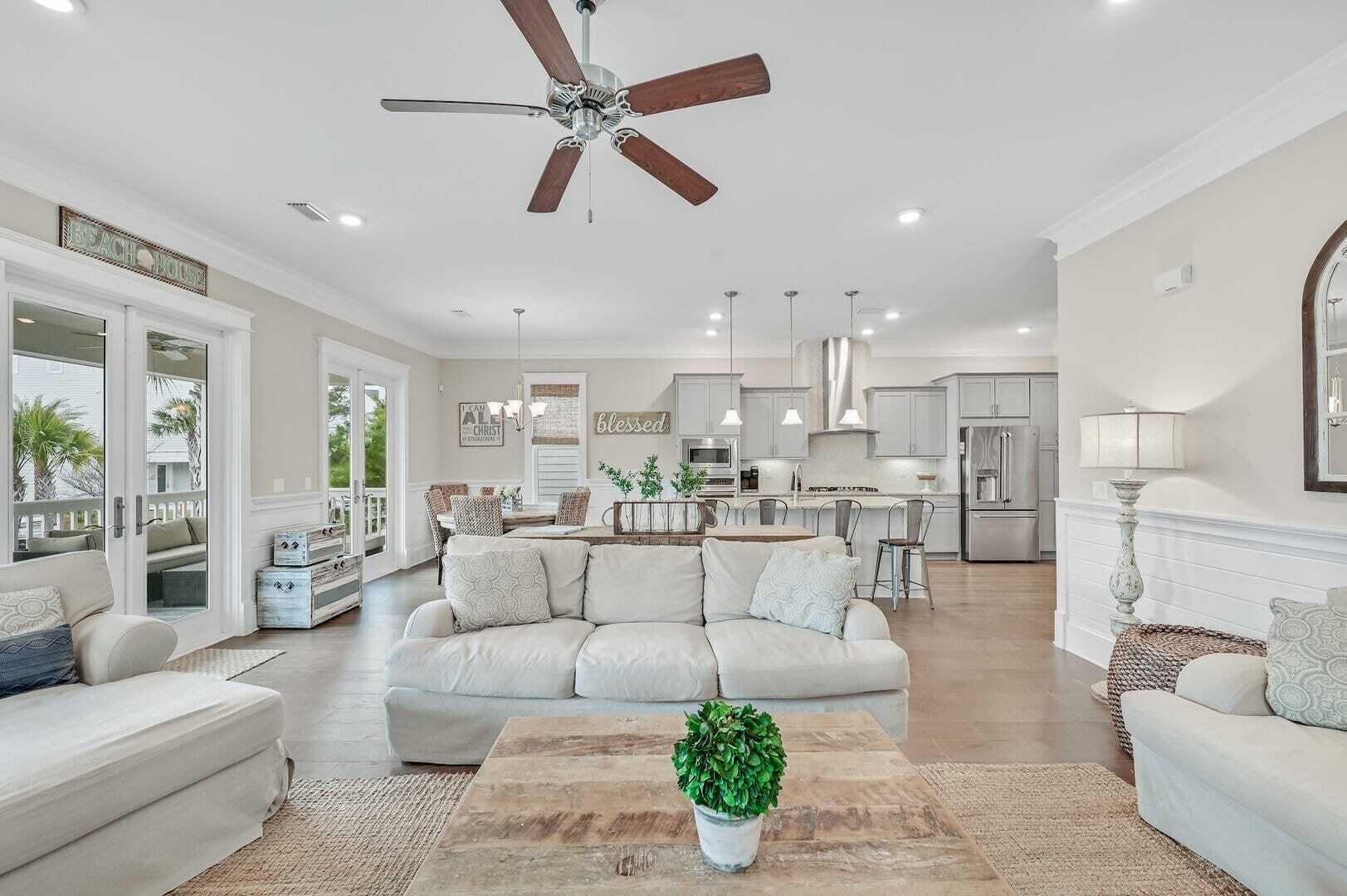 A spacious living room with a large sectional sofa, a ceiling fan, and a view of the kitchen and dining area.