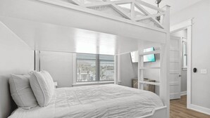 A bedroom with a large bed, a TV mounted on the wall, and a wooden floor.