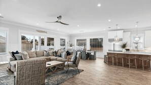 A spacious living area with a large sofa, a coffee table, and a dining set.