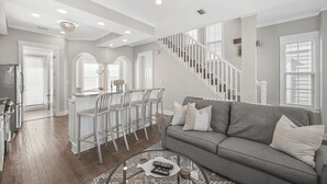 A spacious living room with a grey sofa, a coffee table, and a staircase leading to the upper floor. - Steps to Private Beach Access Pool + Bikes Seacrest 30A (Panama City Beach)