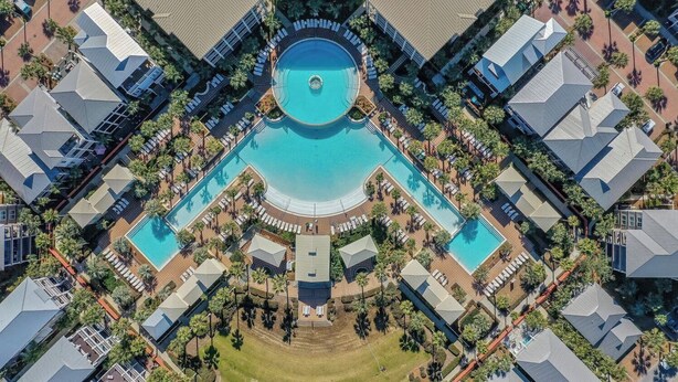 Un complexe hôtelier doté de plusieurs piscines, de palmiers et d’une piscine centrale de forme circulaire.
