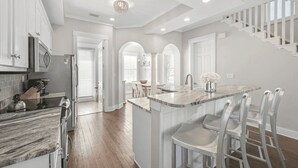 A modern kitchen with marble countertops, stainless steel appliances, and a central island with bar stools. - Steps to Private Beach Access Pool + Bikes Seacrest 30A (Panama City Beach)