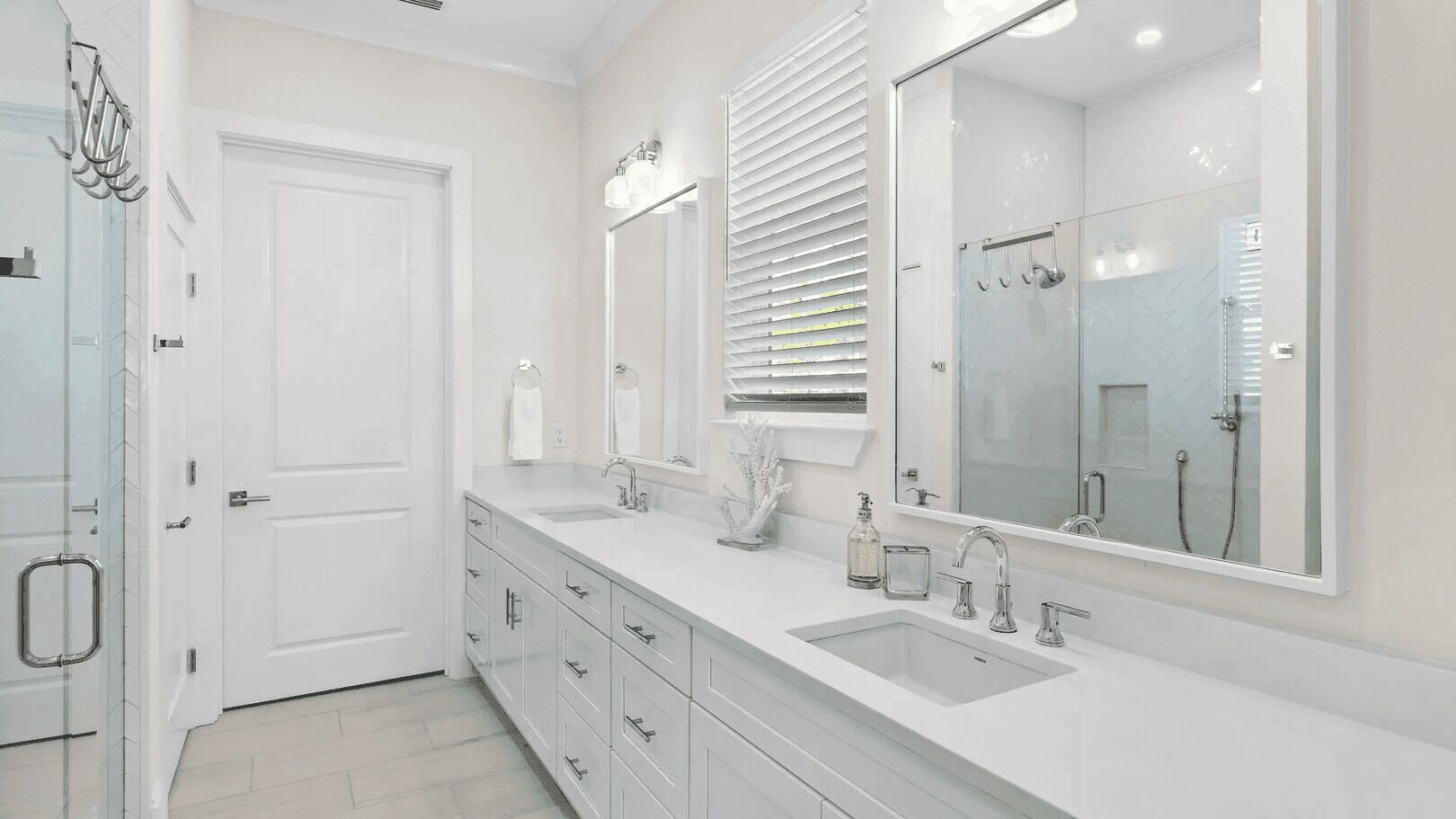 A modern bathroom with a double sink, large mirrors, and a glass shower enclosure.