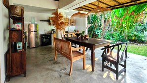 Una cocina con refrigerador, estufa y una mesa de comedor de madera con sillas.