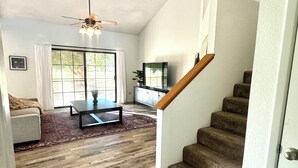 A spacious living room with a wooden floor, a ceiling fan, a staircase, and a large window. - PETS STAY FREE! 2 bed/2.5 ba townhome on Golf Course in the Foothills of Yuma (Yuma)