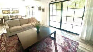 A living room with a sofa, coffee table, and a large window with a view of greenery. - PETS STAY FREE! 2 bed/2.5 ba townhome on Golf Course in the Foothills of Yuma (Yuma)