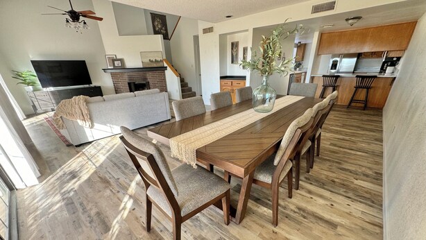 A spacious living area with a wooden dining table, comfortable seating, a fireplace, and a kitchen in the background. - PETS STAY FREE! 2 bed/2.5 ba townhome on Golf Course in the Foothills of Yuma (Yuma)