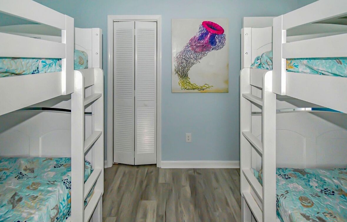 A room with bunk beds, a closet, and a wall-mounted artwork.