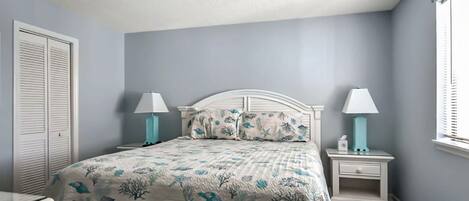 Une chambre à coucher avec un lit, deux tables de chevet, une commode, une fenêtre et une porte.