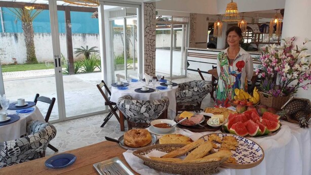 A dining area with tables set for breakfast, featuring a variety of foods and a large floral arrangement. - Czaritza Apart Hotel (Bombinhas)