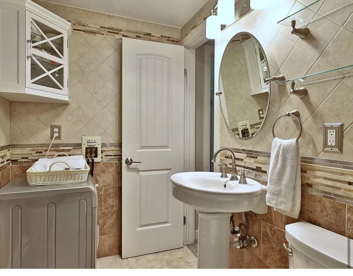 A bathroom with a white sink, a mirror, a towel rack, and a door.