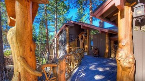 Een houten chalet met veranda, omgeven door bomen.