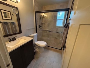 Une salle de bain avec une douche à parois de verre, des toilettes, un lavabo et un miroir.