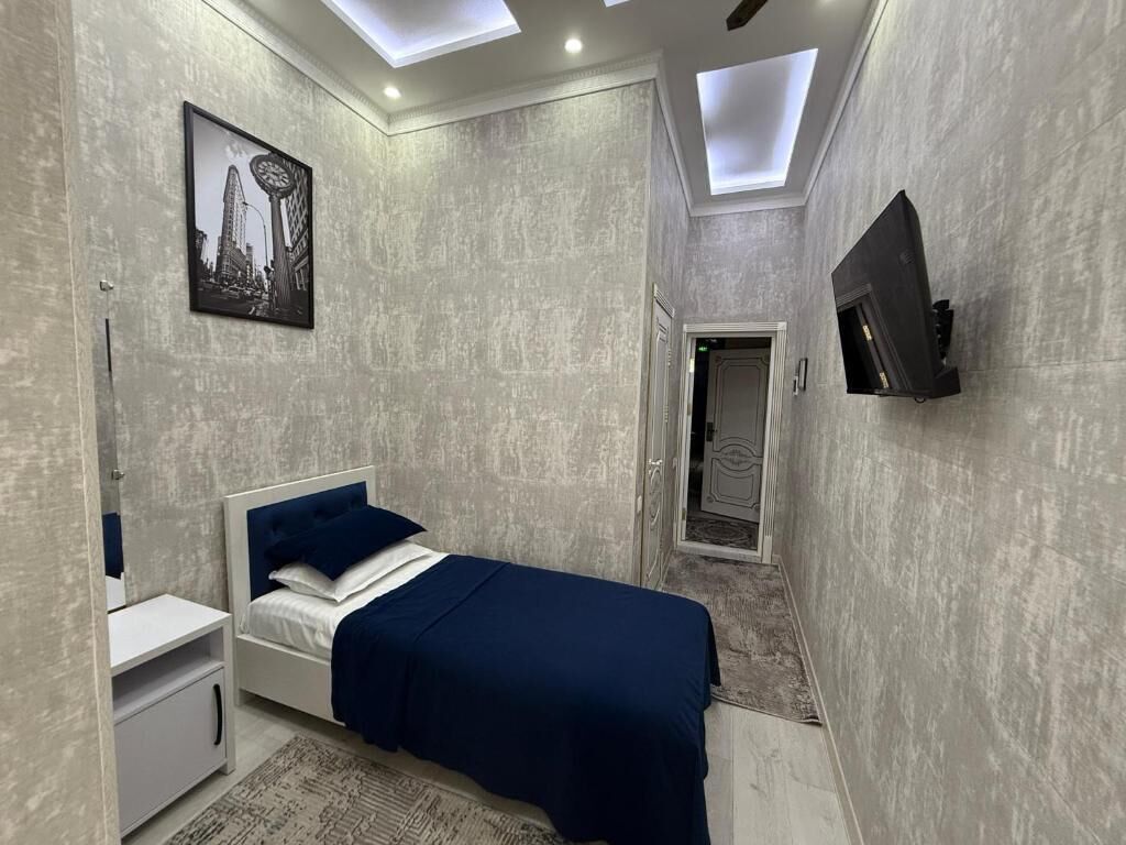 A modern bedroom with a bed, bedside table, and a mounted TV.