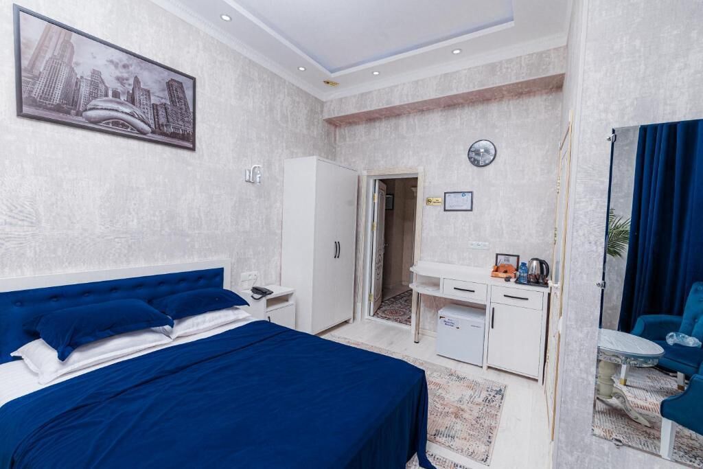 A bedroom with a bed, a desk, a wardrobe, a clock, and a chair.
