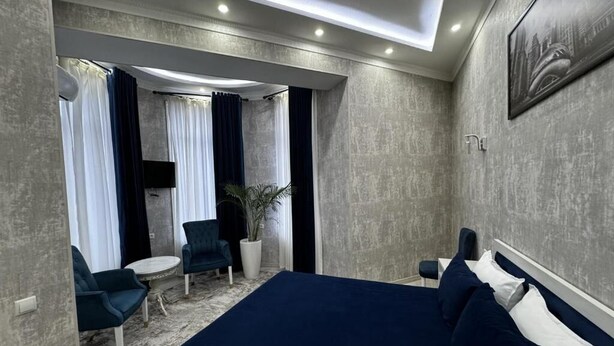A hotel room with a large bed, a seating area with chairs, a small table, and a potted plant.