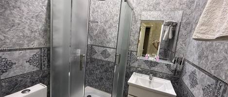 A bathroom with a glass-enclosed shower, a white sink, and a mirror.