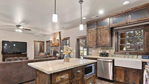 A modern kitchen with wooden cabinets, granite countertops, a built-in oven, and a large island with a sink. - 2,500 Sq Ft Cabin | 2 Living Rooms | BBQ (South Lake Tahoe)