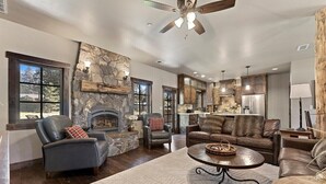 A spacious living area with a stone fireplace, leather sofas, and a large window providing a view of the outdoors. - 2,500 Sq Ft Cabin | 2 Living Rooms | BBQ (South Lake Tahoe)