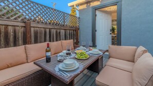 An outdoor patio with a dining table set for four, surrounded by cushioned seating.