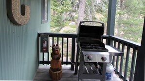 Une véranda couverte avec un barbecue et une sculpture en bois.
