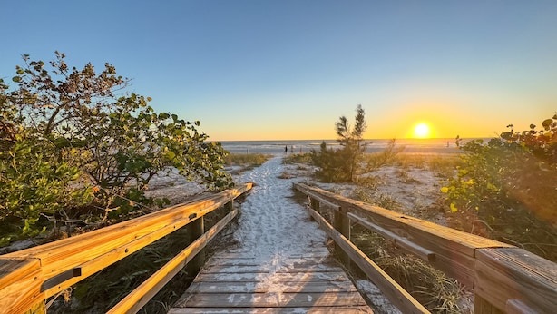 A wooden boardwalk leading to a beach with a sunset in the background. - Luna Sea | Anna Maria Beach Home Rental - Steps from the Sea! (Anna Maria)
