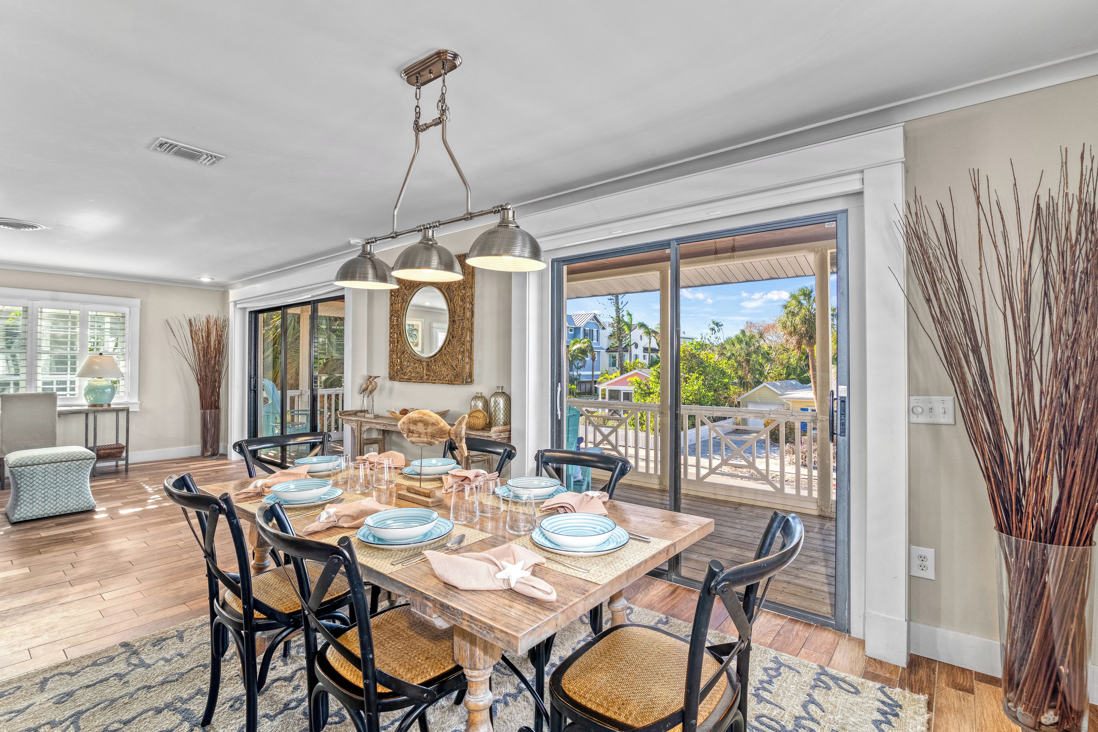 A dining area with a wooden table set for four, surrounded by black chairs with woven seats.