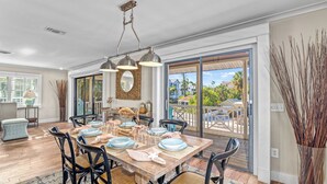 A dining area with a wooden table set for four, surrounded by black chairs with woven seats. - Luna Sea | Anna Maria Beach Home Rental - Steps from the Sea! (Anna Maria)