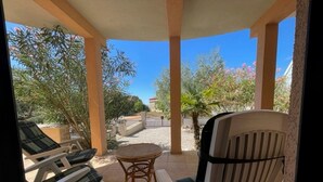 A covered outdoor seating area with lounge chairs and a table, surrounded by trees and a clear sky. - Pleasant Apartment With Pool (Porec)
